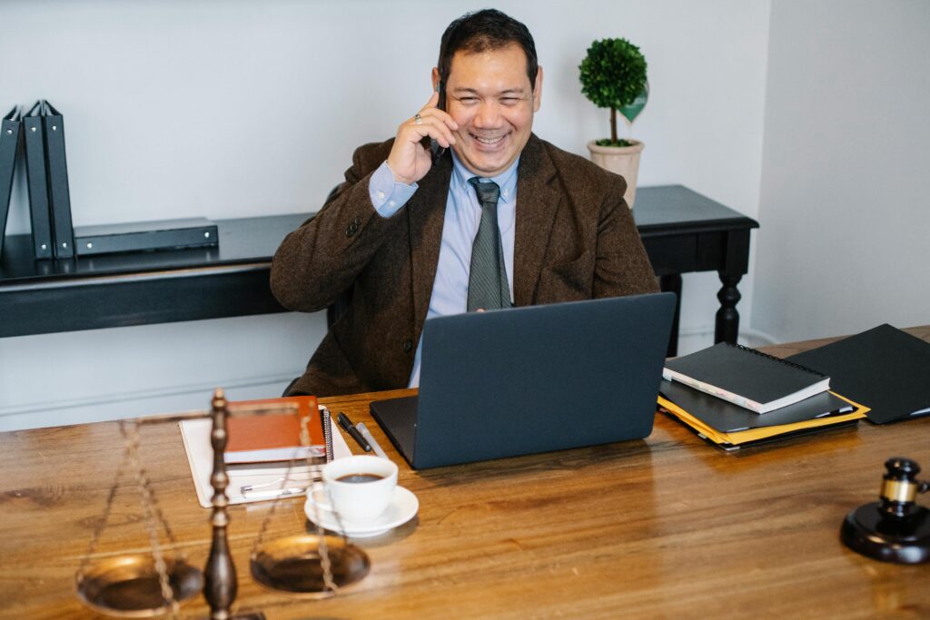 pexels-photo-5668790-5668790 Joyful Asian male lawyer wearing formal suit having conversation on mobile phone and using laptop while working in modern law firm